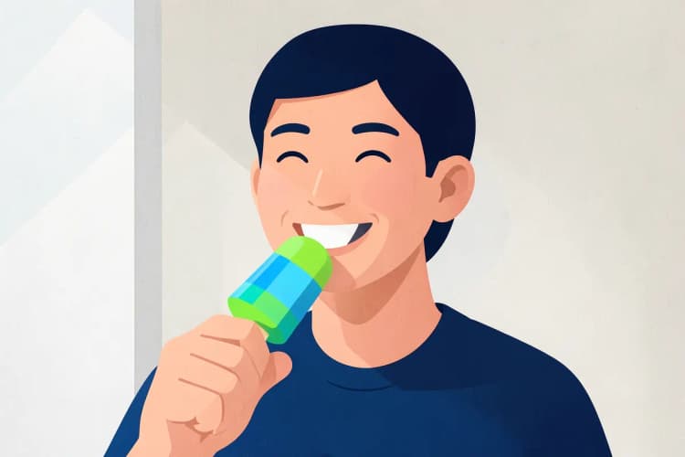 Uma pessoa sorrindo e comendo um picolé, sinal de melhora na recuperação da cirurgia de amígdalas.